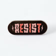 If they think we’re going to take their shit lying down, they can think again. Now is the time to resist. To fight back. To protest. To tell politicians and power trippers where to put their vitriol. And when we are lying down (because we all need a break) we’ll be wearing this pin.